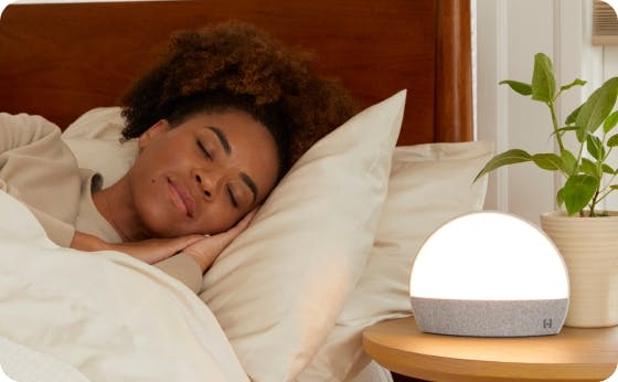 Woman falling asleep in her bed with her Hatch Restore Warm White Reading Light on